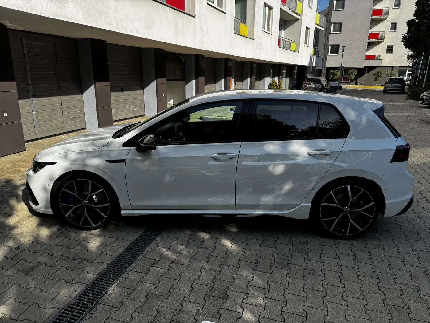 Technik meria hrúbku laku na bočnej časti bieleho auta